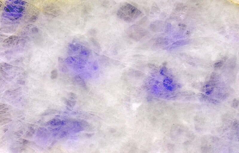 A closeup of lavender jadeite, showing the texture and deep colors of real jade.